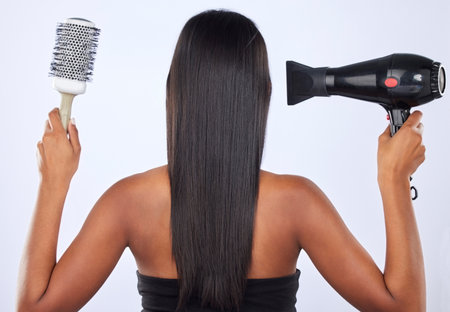 Brush, hair dryer or back of woman in studio for keratin growth, healthy natural shine or wellness. Young girl model, salon spa or self care cosmetics grooming routine isolated on white backgroundの写真素材