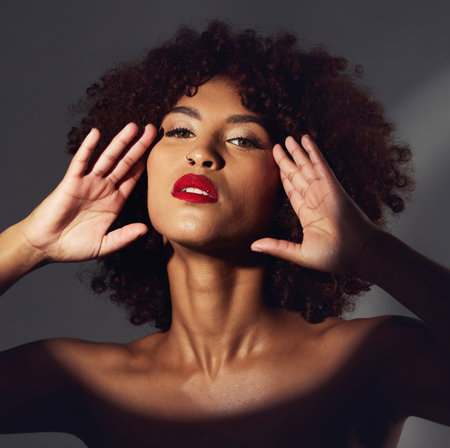 Black woman, red lipstick and spotlight with beauty and makeup in portrait, hands frame face on studio background. Cosmetics, creative and aesthetic with beautiful female, cosmetology and art decoの写真素材