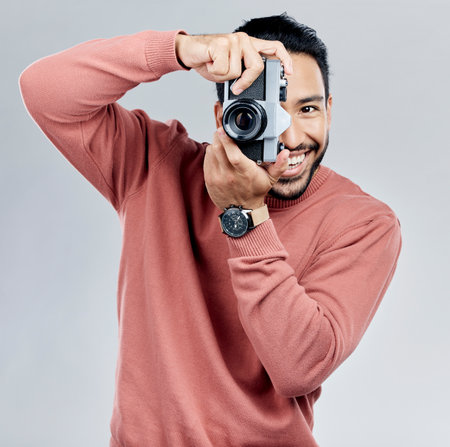 Man with camera, photography in portrait with smile, taking picture with art and smile isolated on studio background. Photographer, happiness and creativity with vintage technology with creative maleの写真素材