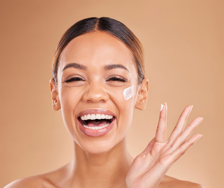 Laughing, skincare portrait or happy woman with cream product for beauty or young face on studio background. Dermatology cosmetics, funny or beautiful girl with facial moisturizer or lotion for glowの写真素材