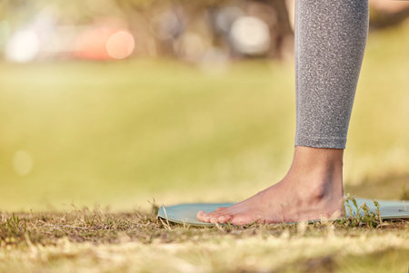 Woman feet, mat and yoga on grass, park and exercise, meditation and spiritual wellness in nature for zen. Female, pilates or cardio person with workout training for peace, calm and healthy lifestyleの写真素材
