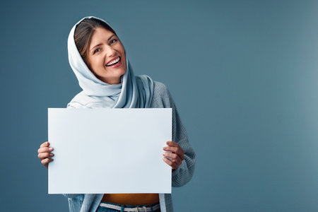 Your copy here. Studio portrait of an attractive young woman holding a blank sign against a grey background.の写真素材