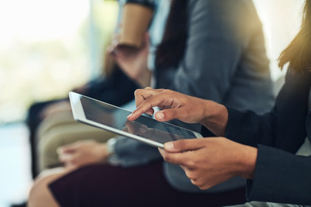Digitizing her conference notes. a businesswoman using a digital tablet during a conference in a modern office.の写真素材