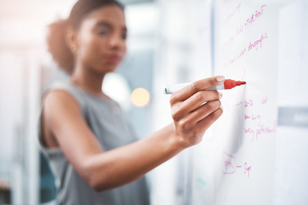 Shes got the gift of efficient strategic planning. a young businesswoman brainstorming on a whiteboard in modern office.の写真素材
