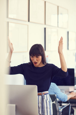 When technology attacks. a young businesswoman using a computer and looking stressed out at her desk...