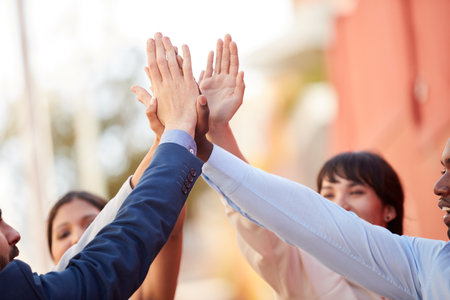 United in the same mission. a group of businesspeople high fiving together outdoors.の写真素材