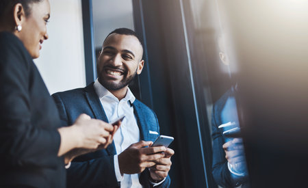 The fast-paced business world requires instant connections. two businesspeople using their cellphones in an office.の写真素材