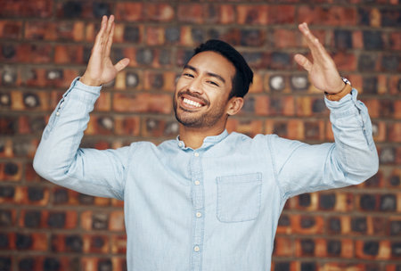 Happy, excited and portrait of asian man and brick wall background for confidence, trendy and natural. Pride, cool and style with male and arms up for laughing, happiness and goofy expressionの写真素材