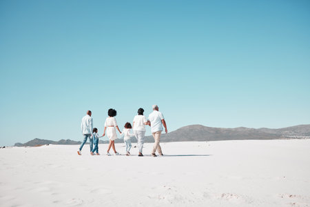 Mother, dad and children with grandparents on beach to relax on summer holiday, vacation and weekend. Happy family, parents and back of kids, grandpa and grandma for walking, bonding and quality timeの写真素材