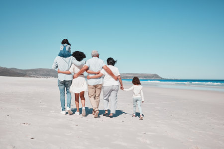 Back of family on beach walking with children to relax on summer holiday, vacation and weekend together. Travel mockup, ocean and grandparents, parents and kids hug for bonding, quality time and calmの写真素材