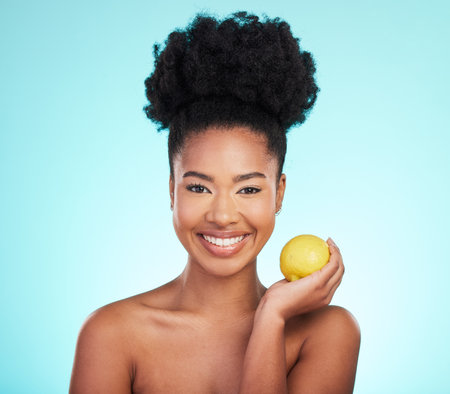 Lemon beauty, portrait and happy black woman in studio, blue background and vegan wellness. Happy model, citrus fruits and smile for facial cosmetics, vitamin c skincare and natural detox dermatologyの写真素材