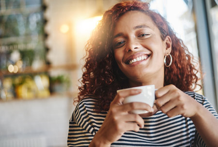 Coffee is a great way to spend time with you. Portrait of an attractive young woman enjoying a cup of coffee in a cafe.の写真素材