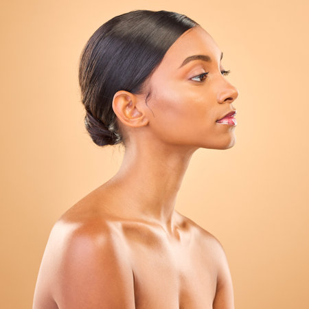 Beauty, face and profile of woman in studio for skincare, cosmetics, dermatology or makeup. Aesthetic female .serious about self care, natural skin and spa facial shine results on a brown backgroundの写真素材