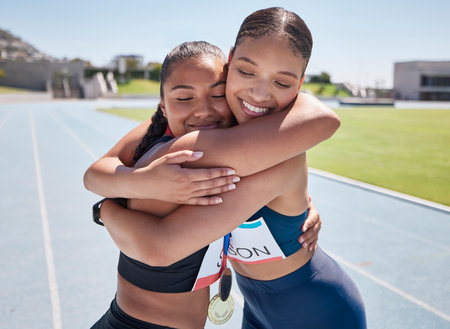 Fitness, success and runner hug winner after marathon race on a running track, happy, excited and congratulations. Sports, friends and women embrace in support of achievement, performance and goalの写真素材