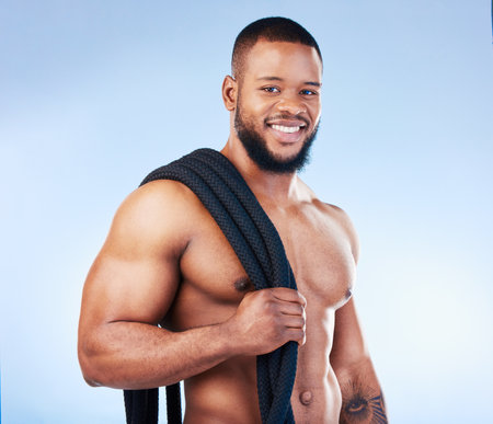 Fitness, man and portrait smile with rope for intense workout, exercise or training against blue studio background. Happy face and fit muscular male model holding thick ropes for exercising on mockupの写真素材