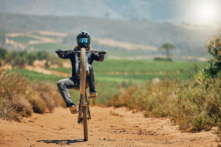 Cycling, fitness and person on a bicycle in the countryside for extreme sport, adrenaline and fun. Speed, action and cyclist on a dirt road for stunt, trick or training, freedom and balance in natureの写真素材