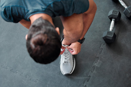 Top view, man and tie shoes in gym to start workout, training or exercise for sports. Athlete, male and tying laces on sneakers to prepare for running, cardio or exercising for health or fitness.の写真素材