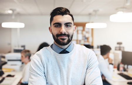 Success is all about attitude. Cropped portrait of a handsome young businessman in the office while his colleagues are working in the background.の写真素材