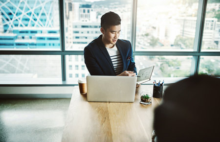 The office with a collaborative culture. two young businessmen working together at a desk in a modern office.の写真素材