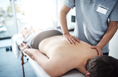 Youve been holding too much tension in your back. Closeup shot of an unrecognizable physiotherapist treating a patient.の写真素材