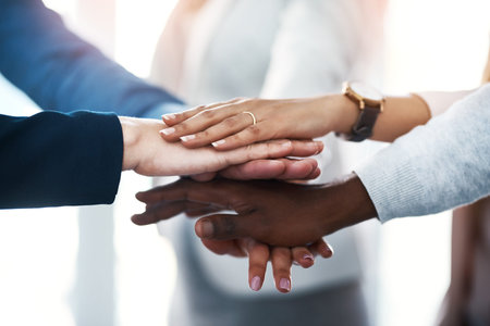Lets do it together. a group of unrecognizable businesspeople putting their hands together in a...
