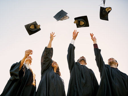 Even if its tough, you can still triumph. a group of students throwing their hats in the air on graduation day.の写真素材