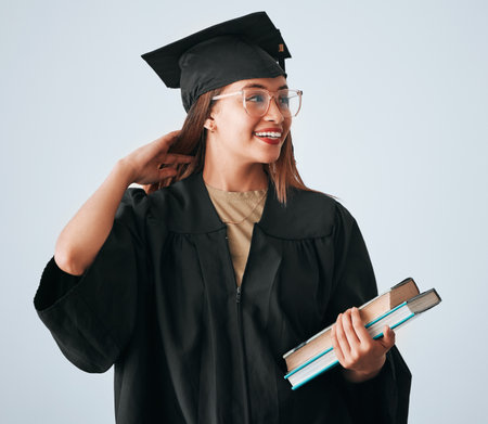Graduation cap, books and woman isolated on studio background for happy education, college or scholarship success. Biracial university student or graduate with reading knowledge and learning goalsの写真素材