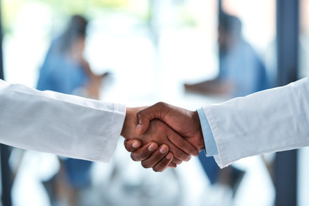 Coming together as one. Closeup shot of two unrecognizable doctors shaking hands in a hospital.の写真素材