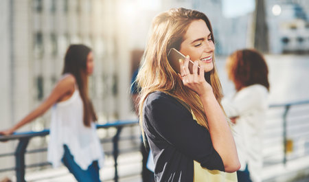 Your calls are always welcome. an attractive young woman making a phone call while standing outside.の写真素材