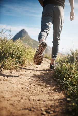 Keep moving towards a healthier you. Low angle shot of an unrecognizable man out running.の写真素材