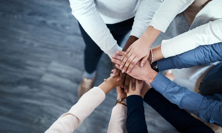 The secret is always teamwork. High angle shot of a group of unrecognizable businesspeople putting their hands together in a huddle.の写真素材
