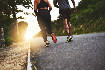Everything is better with a partner. Low angle shot of an unrecognizable couple out running together.の写真素材