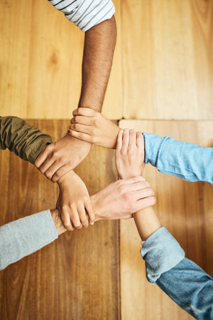 Supporting one another. High angle shot of a group of unrecognizable university students holding one anothers wrists as a show of solidarity.の写真素材
