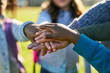 Were gonna stick together as friends. a group of unrecognizable elementary school kids joining their hands together in a huddle outside.の写真素材
