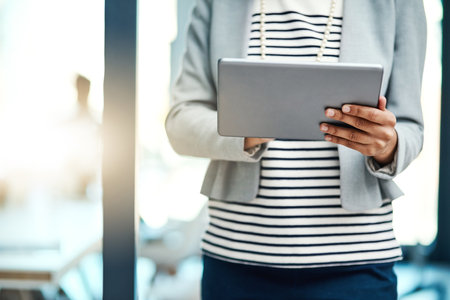 Tools that were designed for business efficiency. an unrecognisable businesswoman using a digital tablet in an office.の写真素材