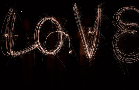 Lets light this place up. the word love being drawn with a sparkler through use of light painting outside at night.の写真素材