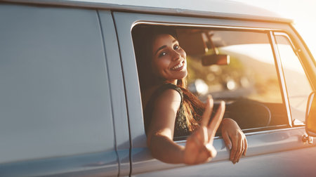 Im off to live my life. a young woman leaning out of a vans window and showing a peace sign on a roadtrip.の写真素材