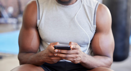 Fitness, hands and phone in gym with man after workout, training or wellness exercise with social media. Strong, muscular and black man text contact, internet or web app in a health and wellness clubの写真素材