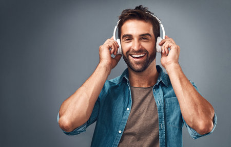 Its my feel good song. Studio shot of a handsome young man wearing headphones against a grey...