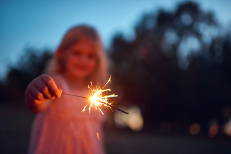 Shes lighting up the night. an unrecognizable little girl playing with a sparkler at night time outside in nature.の写真素材