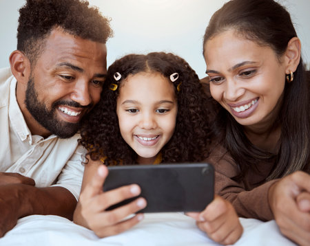 Black family, phone and child on bed for video, smile or happy for streaming, cartoon or movie. Mom, dad and kid with smartphone in bedroom to game, internet or watching to relax, happiness or playの写真素材