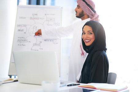 Evaluating the state of business as a team. Portrait of a young muslim businesswoman sitting in on a presentation with her colleague at work.の写真素材