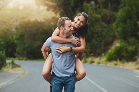 Love is the best feeling in the world. Portrait of a happy young couple enjoying a piggyback ride outdoors.の写真素材