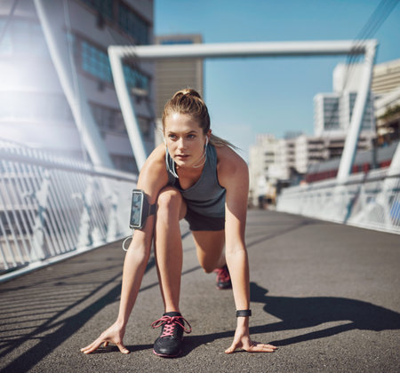 Steadily improving her fitness levels. a sporty young woman getting set for a run.