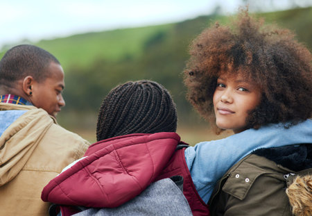 Good friends and the great outdoors. Portrait of a young woman looking over her shoulder while...