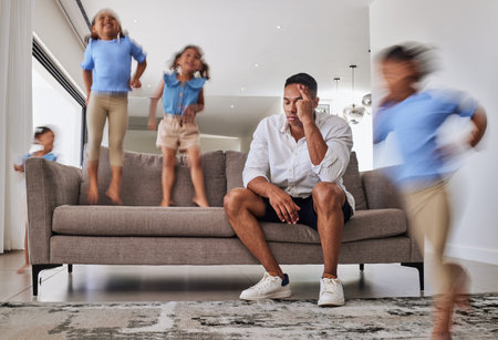 Stress, headache and father with adhd kids running, jumping and playing in family home or house living room. Mental health, burnout or anxiety for parent with autism, energy and hyper active childrenの写真素材