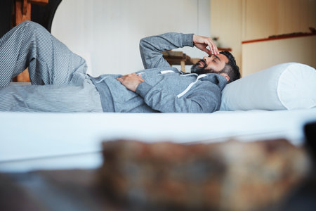 I can only take so much. a mature man lying on his bed feeling exhausted.の写真素材