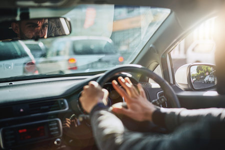 Sounding his annoyance on the road. a young man hooting while driving a car.の写真素材
