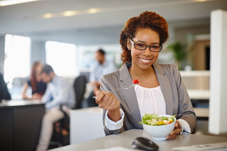 Refuel with healthy food. Portrait of a young businesswoman having a salad during her lunch break at her desk.の写真素材