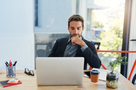 Lets see how many people will like this idea. a handsome young businessman sitting behind his laptop in his office.の写真素材